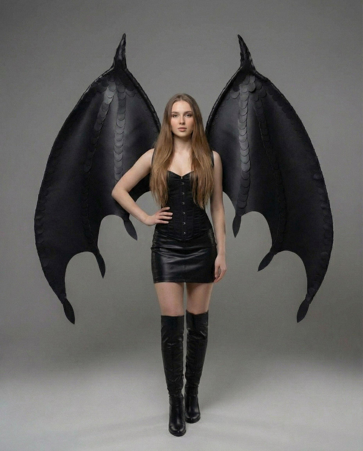 May include: Large black dragon-style wings featuring a structured frame and layered scale-like detailing. The wings are designed to be worn on the back, extending upwards and outwards with pointed tips and curved edges, crafted from a matte black material.