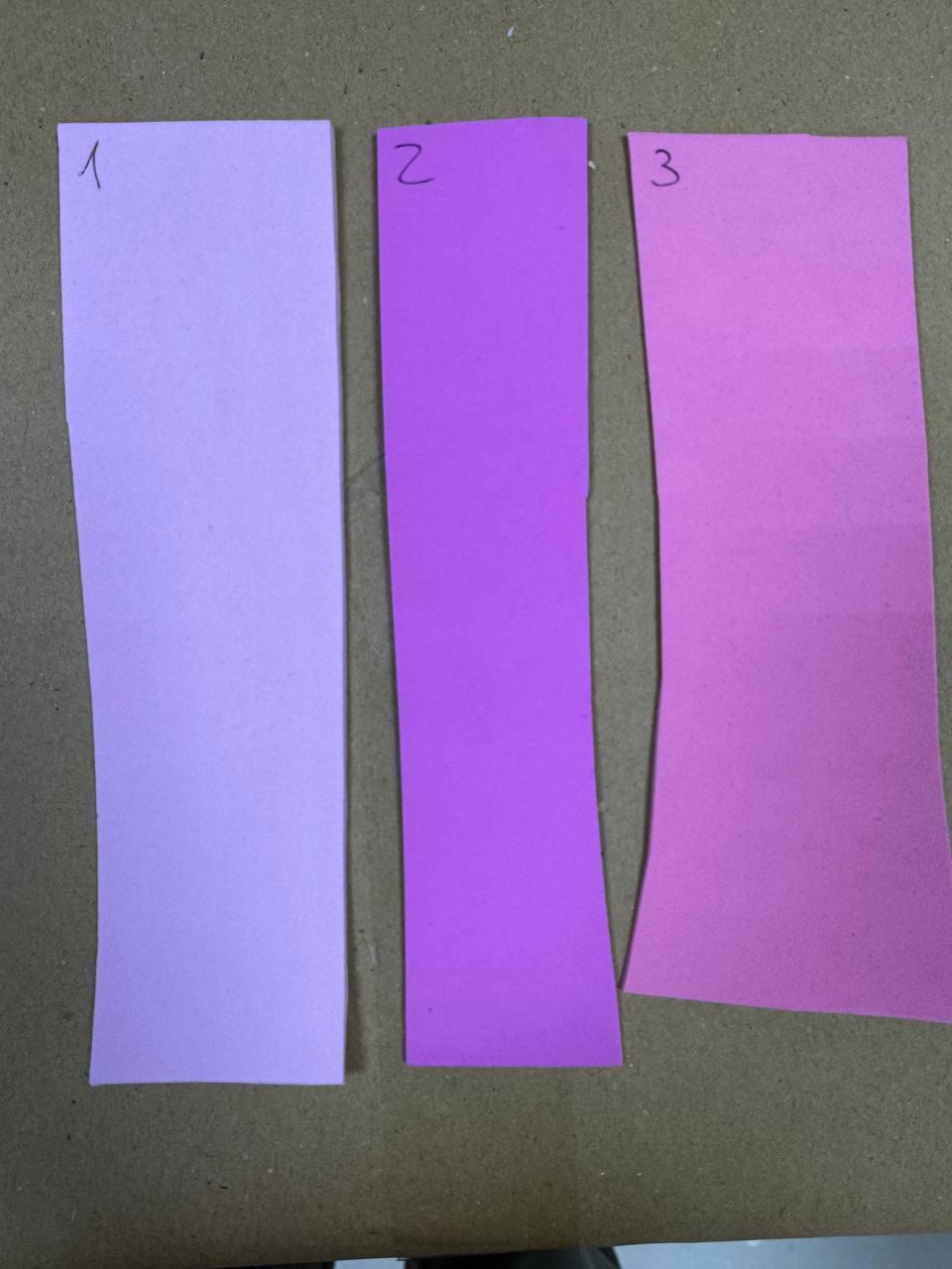 May include: Three rectangular strips of paper arranged side by side. The first strip is light lavender, the second is a vibrant medium purple, and the third is a bright magenta pink. Each strip is labeled with a handwritten number 1, 2, or 3.