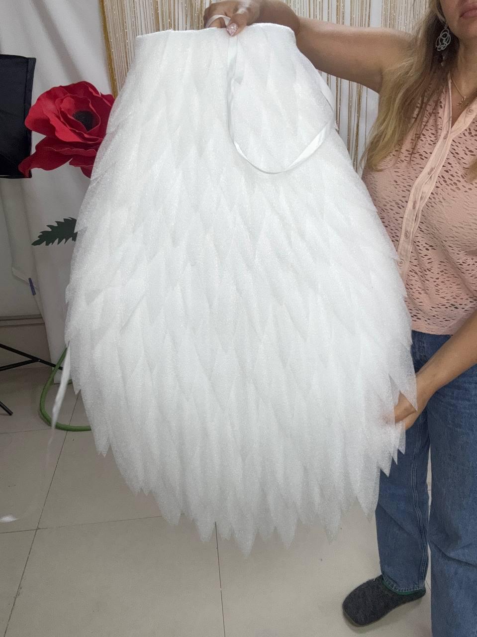 May include: A large, white, semi-circular decorative piece constructed from numerous overlapping, pointed, petal-like fabric layers. The material has a subtle, shimmering, glittery texture throughout, and it features a white ribbon loop at the top.