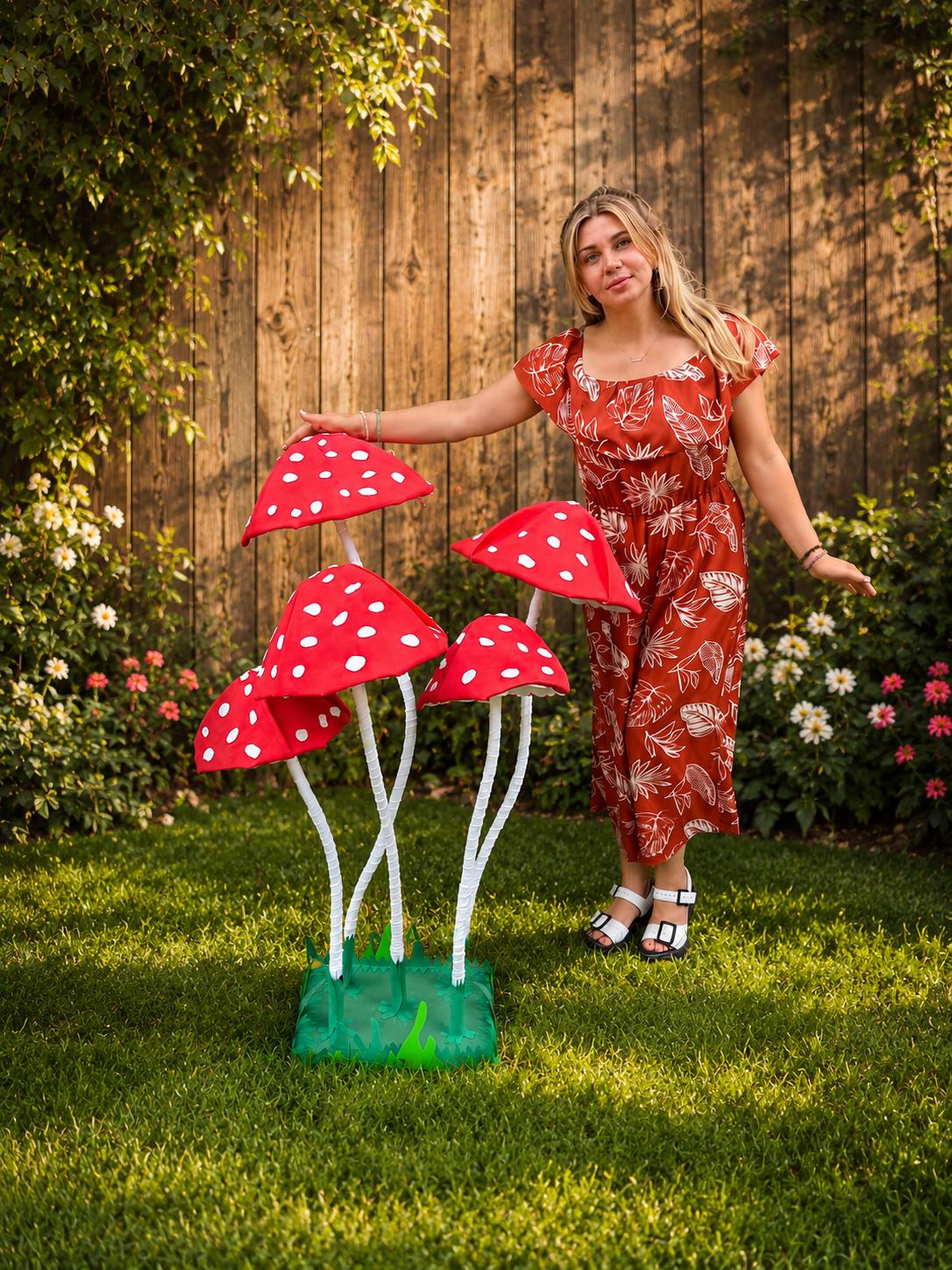 May include: A set of four large, decorative artificial mushrooms featuring bright red caps with white polka dots and long, slender white stems. The mushrooms are attached to a green, square-shaped base with jagged edges resembling grass.