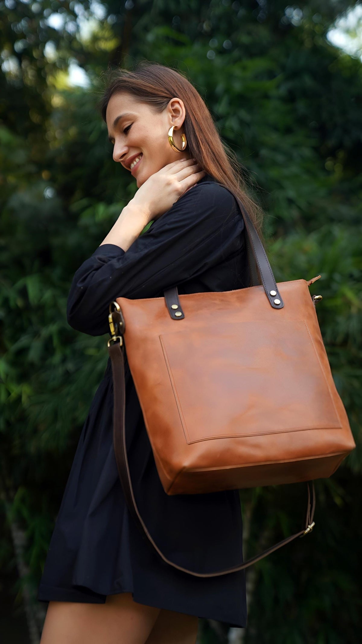 May include: A tan leather tote bag featuring a large rectangular front pocket, dark brown leather shoulder straps secured with silver-toned metal rivets, and a detachable dark brown crossbody strap with gold-toned metal swivel clasps.