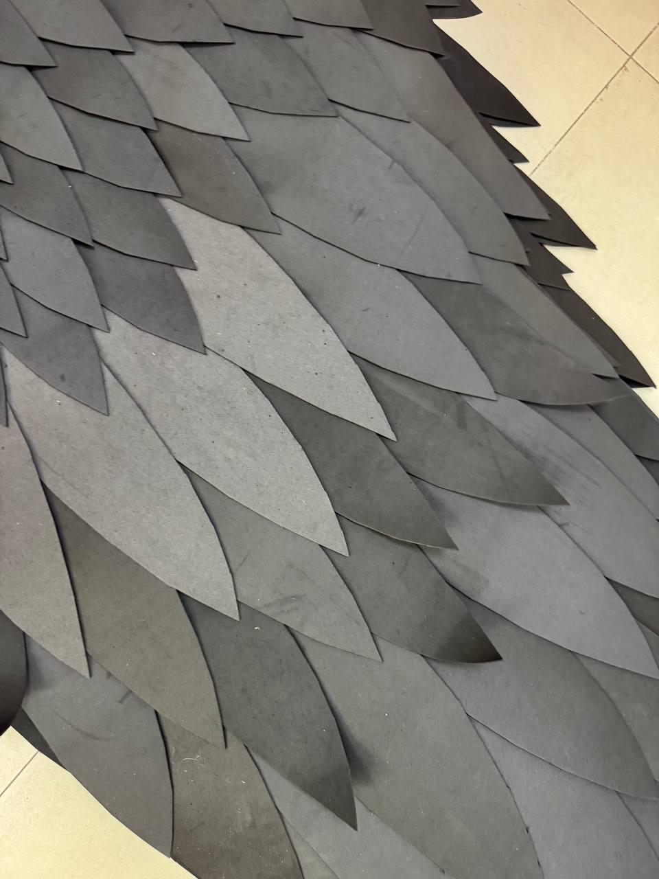 May include: A layered arrangement of numerous pointed, leaf-shaped pieces in varying shades of charcoal, slate, and dark gray. The individual segments are overlapped in a repeating pattern, creating a textured, scale-like surface across the entire frame.
