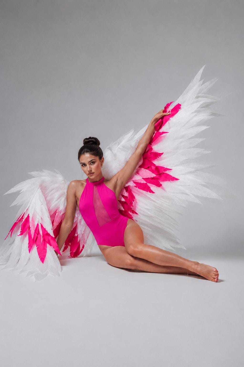 May include: A bright fuchsia bodysuit featuring a high halter neckline with a sheer vertical mesh panel down the center. Large, expansive wings are attached, constructed from layers of white feathers with vibrant fuchsia accents at the base.