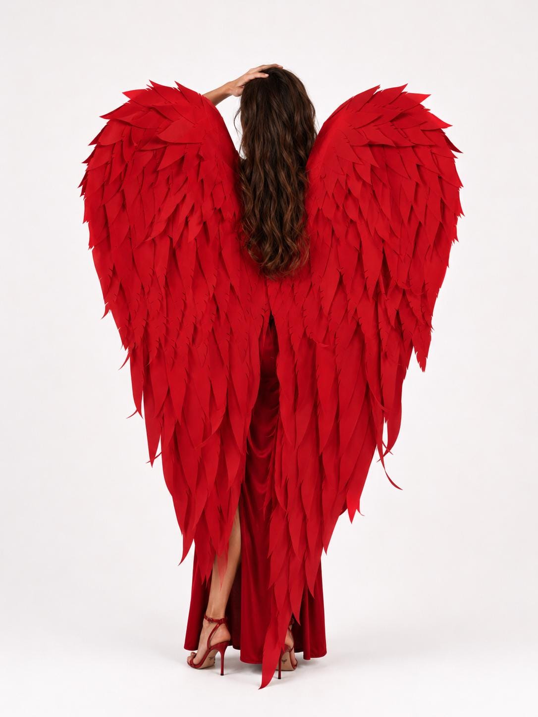 May include: Large, vibrant red decorative wings featuring layered, feather-shaped cutouts. The wings are worn over a matching red floor-length dress with a high side slit and red strappy high-heeled sandals, creating a bold, monochromatic look.