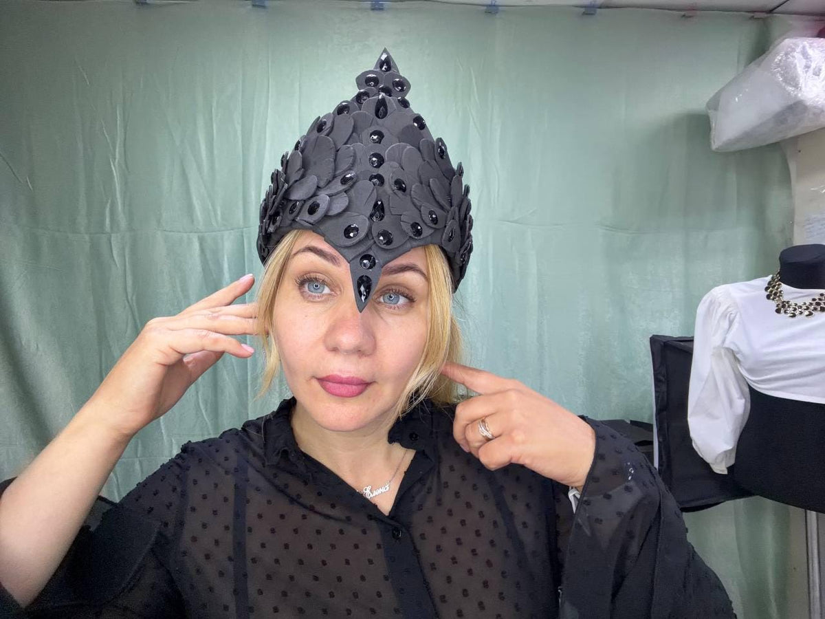 May include: A pointed black headpiece featuring a layered petal-like design adorned with numerous small, shiny black teardrop-shaped crystals. The structure is rigid and covers the upper forehead with a central downward-pointing crystal accent.