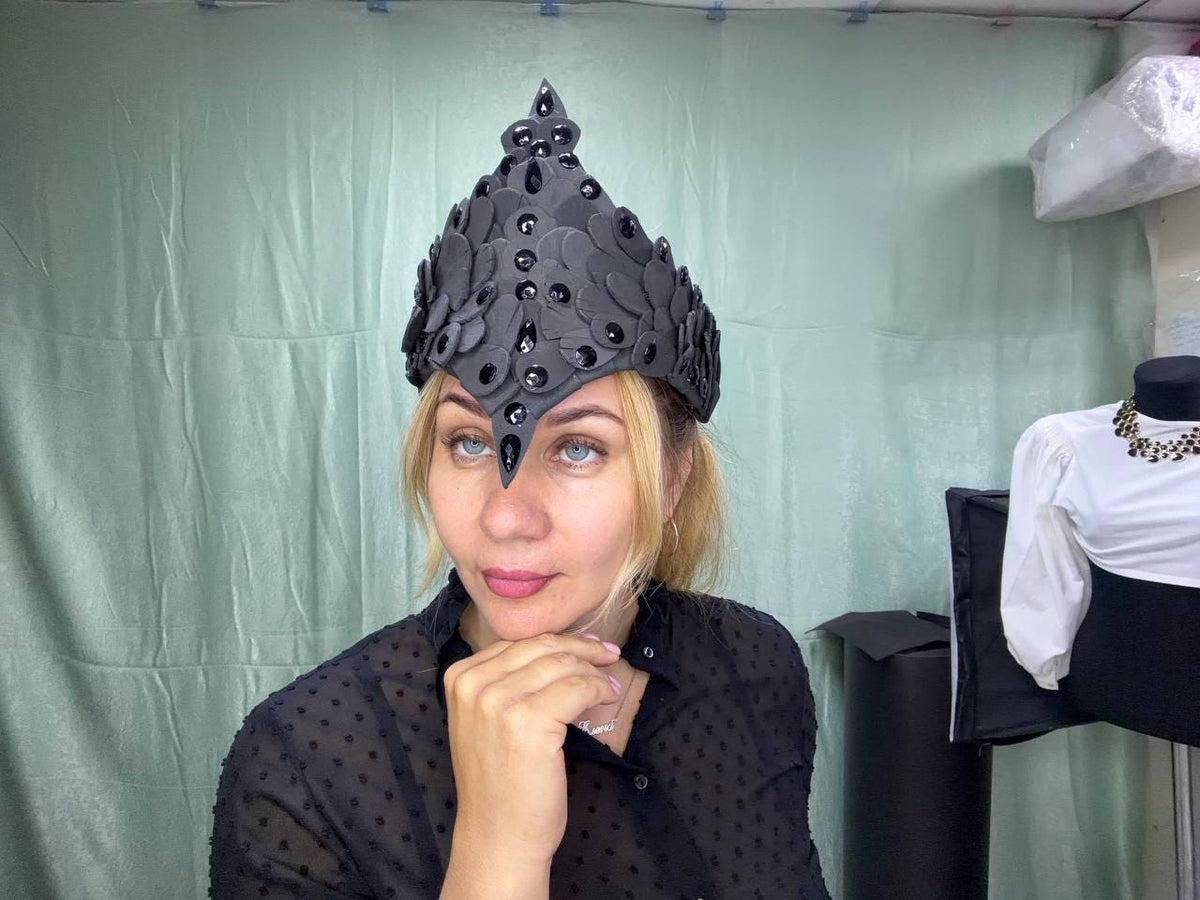 May include: A pointed black headpiece featuring a layered petal-like design constructed from matte material. The crown is embellished with numerous glossy black teardrop-shaped and circular studs arranged in vertical lines along the center peak.