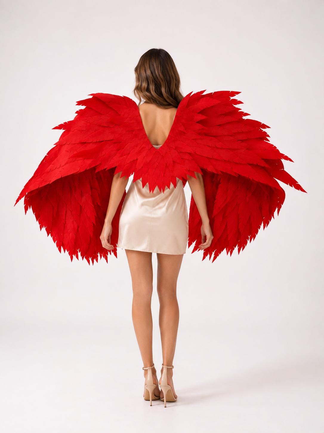 May include: Large, vibrant red wings featuring layered, pointed feather-like structures that extend outward from the center. The wings are attached to a beige slip dress, creating a striking contrast between the bold red color and the neutral garment.