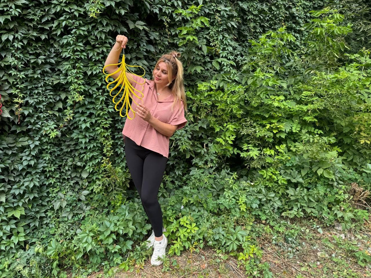 May include: A bright yellow, expandable, spherical geometric toy made of interconnected plastic loops. The object features a series of curved, flexible slats that can be pulled outward to expand its shape or pushed inward to collapse it into a compact form.