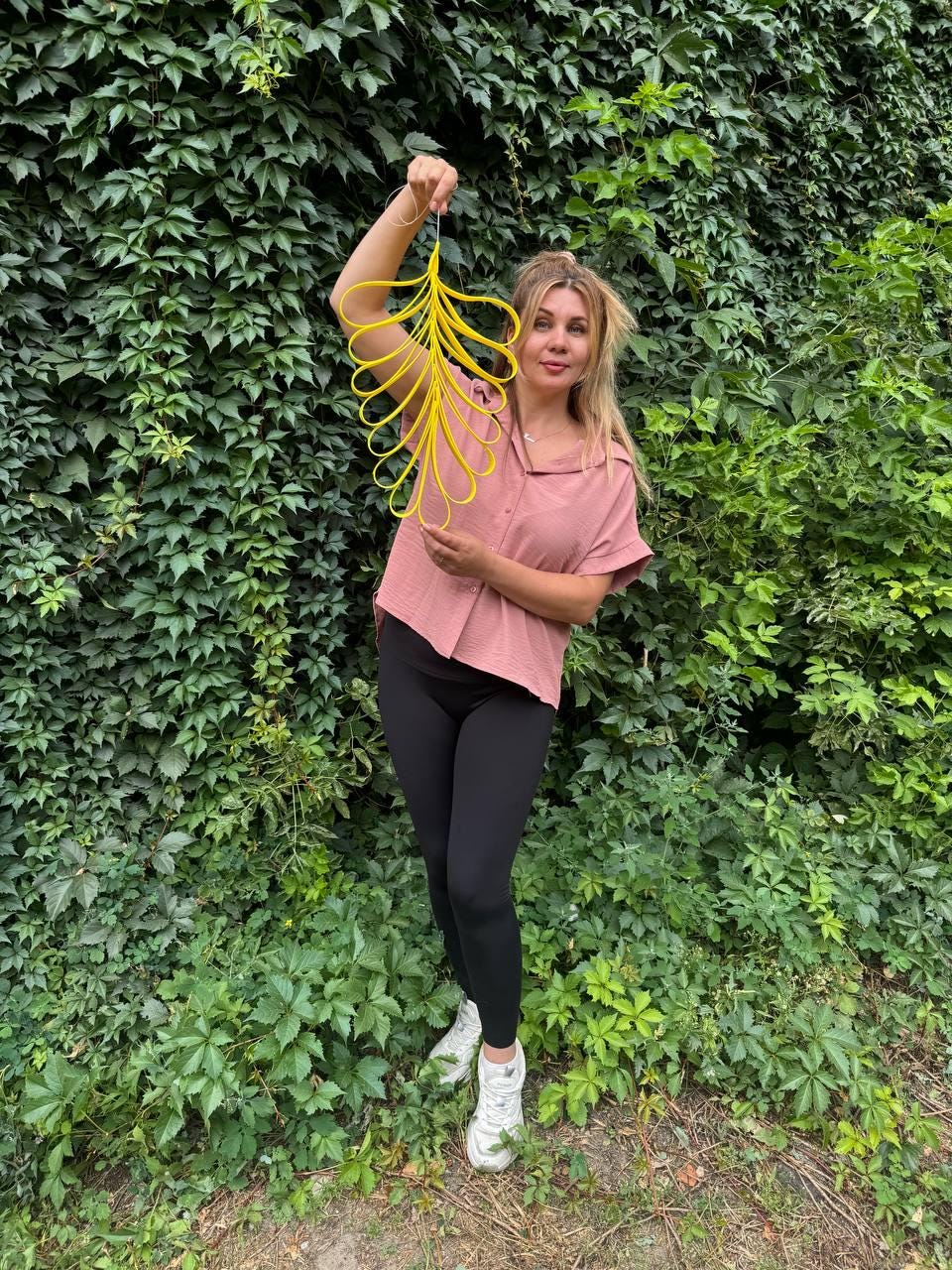 May include: A bright yellow decorative wall hanging shaped like a large leaf, constructed from multiple interconnected loops of material. The object features a symmetrical, elongated design with a central spine and radiating curved segments.