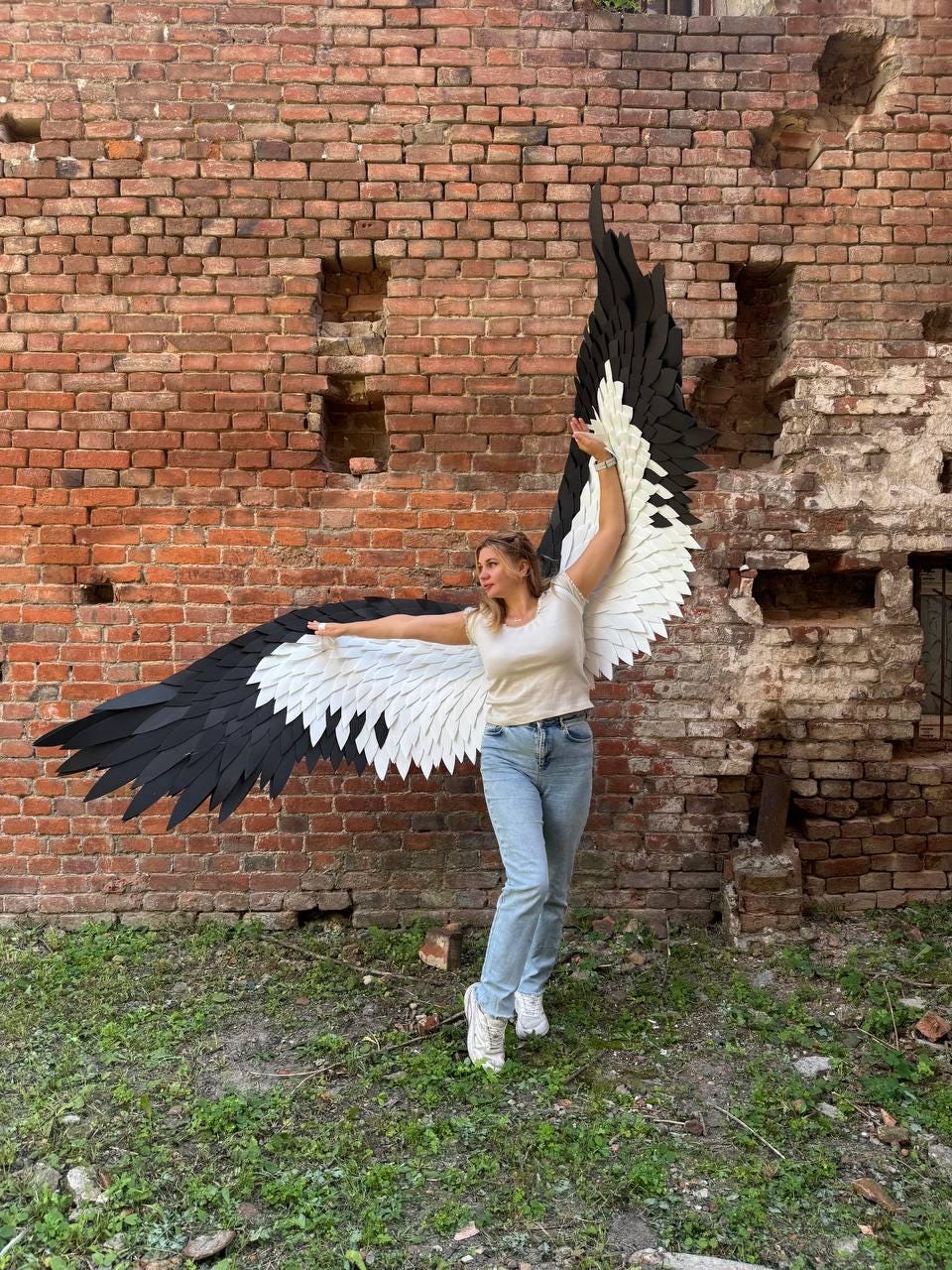 May include: Large decorative wings featuring a layered design with black feathers on the outer edges and white feathers toward the center. The wings are constructed with individual feather-shaped segments that create a textured, expansive appearance.