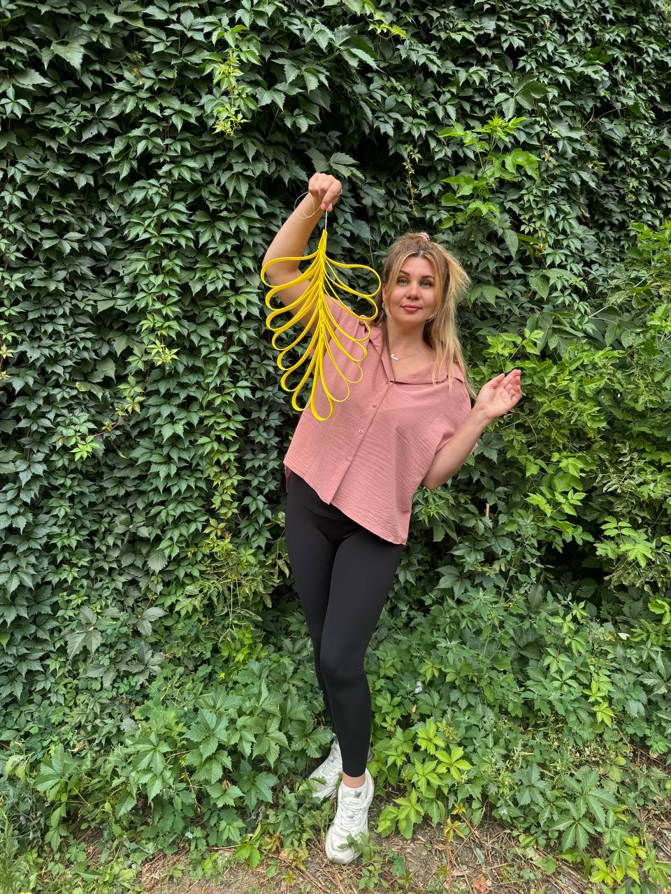 May include: A bright yellow, leaf-shaped decorative hanging ornament constructed from multiple interconnected, flexible loops. The structure features a central spine with symmetrical, cascading curved segments that create a distinct, elongated, and organic silhouette.